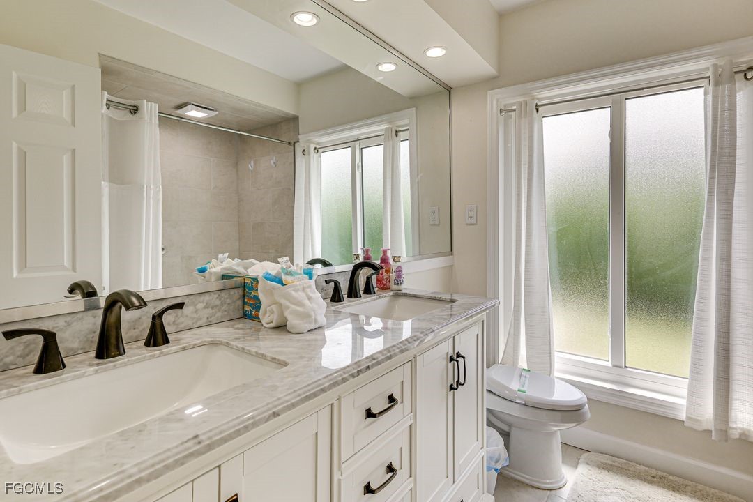 15340 River By Road Fort Myers, FL 33908 - Photo 11 of 21 a bathroom with double vanity sinks a toilet and a large mirror