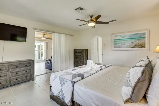 a bedroom with a bed a mirror on dresser and a flat screen tv