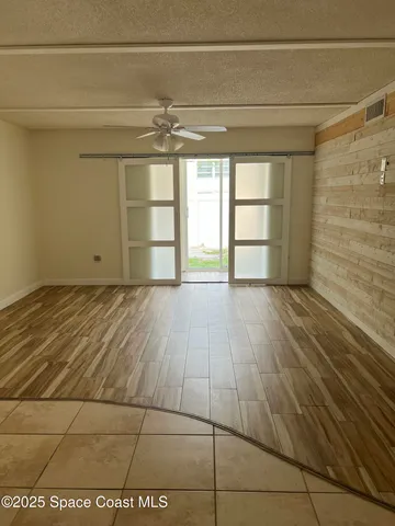 a view of empty room with wooden floor and fan