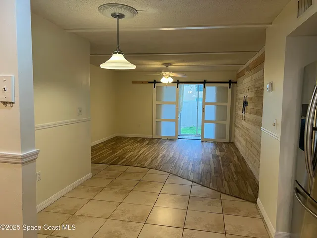 a view of a room with wooden floor and a ceiling fan