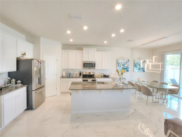 a view of kitchen with stainless steel appliances kitchen island granite countertop a table and chairs
