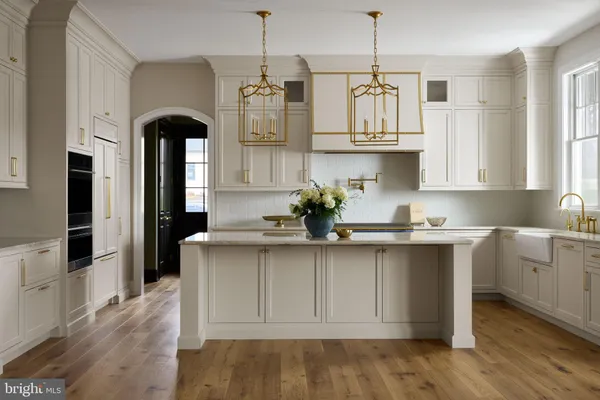 a kitchen with kitchen island granite countertop a stove a sink and white cabinets with wooden floor