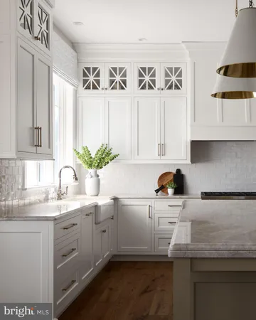 a kitchen with stainless steel appliances white cabinets a sink and a potted plant