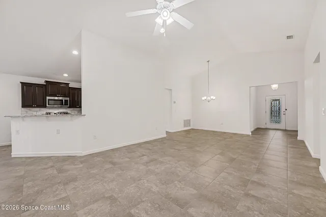 a view of an empty room with kitchen and a window