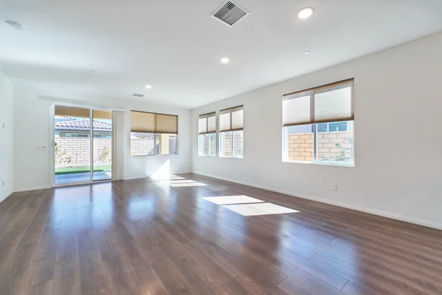 a view of an empty room with kitchen and window