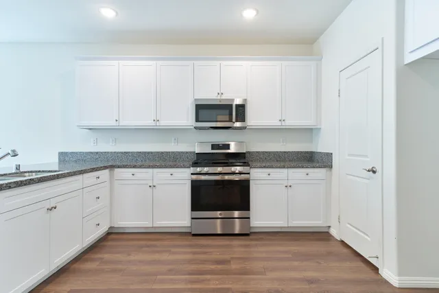 a kitchen with granite countertop white cabinets and stainless steel appliances