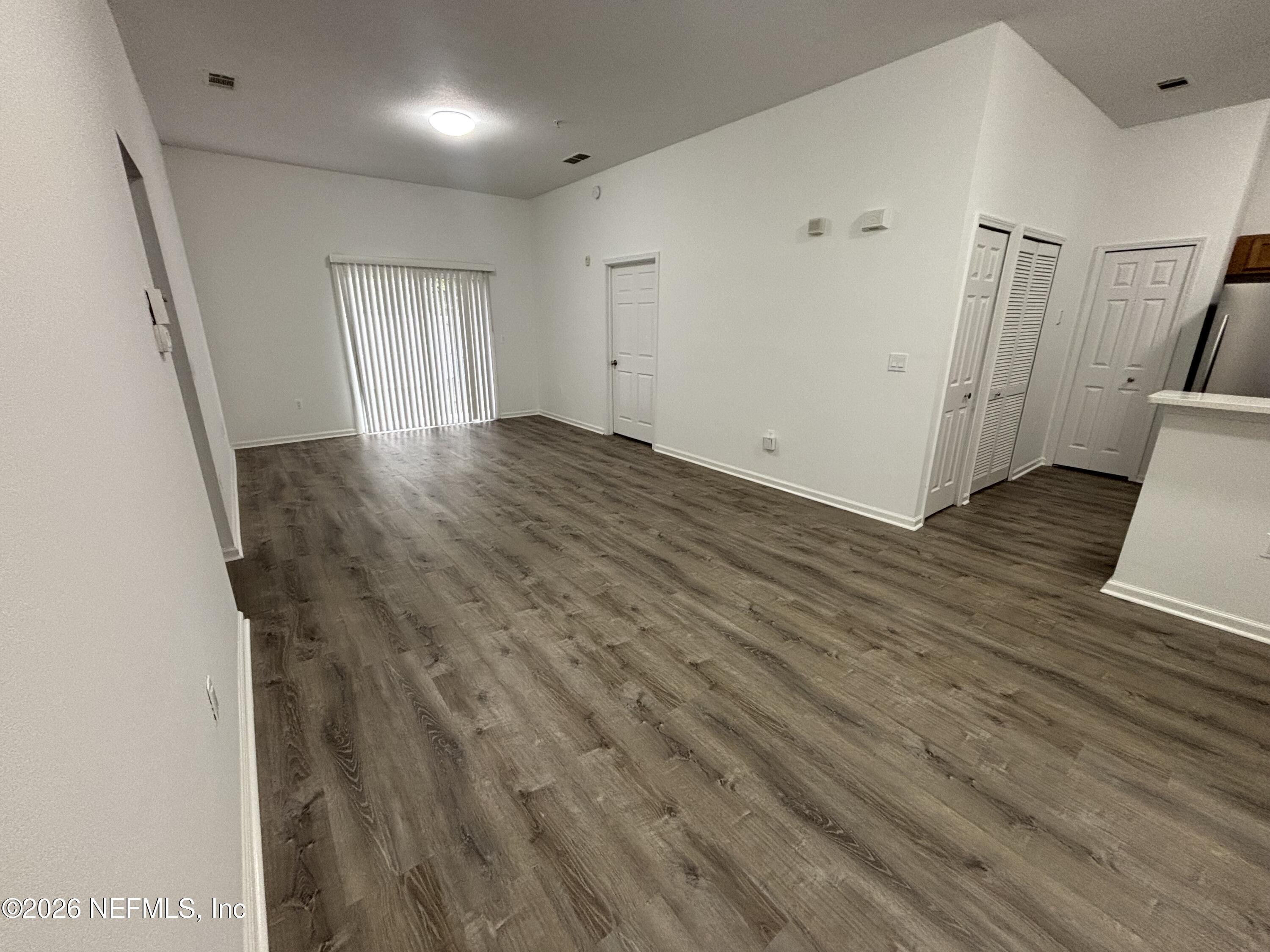 9627 Belda Way, Unit 8 Jacksonville, FL 32257 - Photo 7 of 27 a view of an empty room with wooden floor and a window