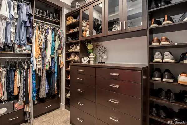 a view of walk in closet with clothes and shoes