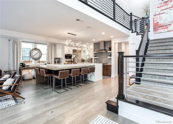 a dining hall with stainless steel appliances kitchen island granite countertop a dining table chairs and couches with wooden floor