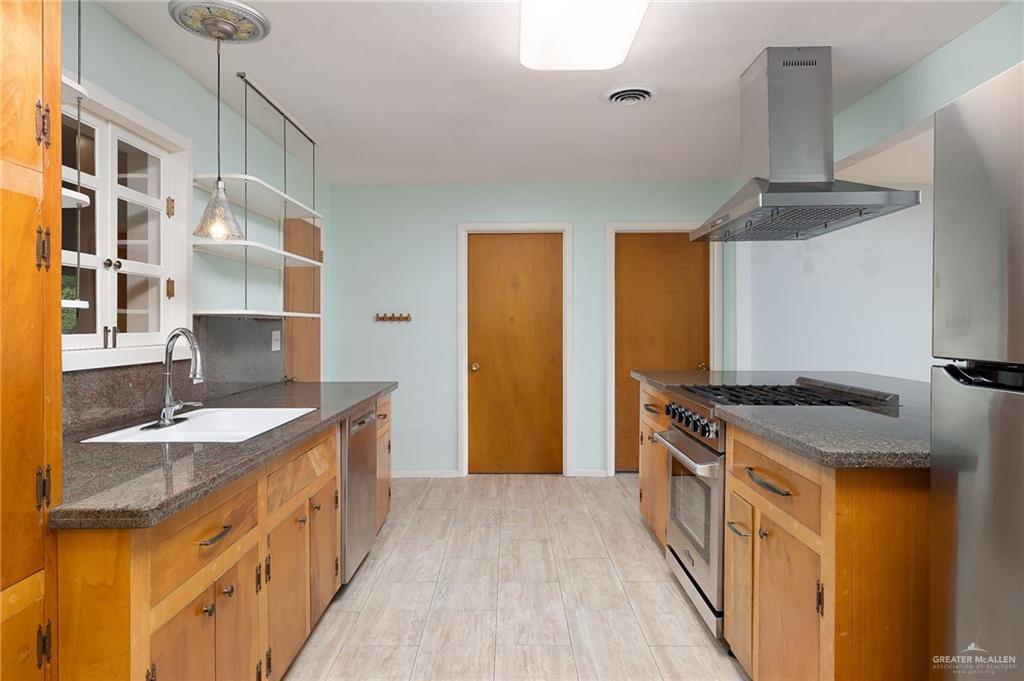 1001 West 7th Street Weslaco, TX 78596 - Photo 5 of 24 a kitchen with stainless steel appliances granite countertop a sink stove and refrigerator