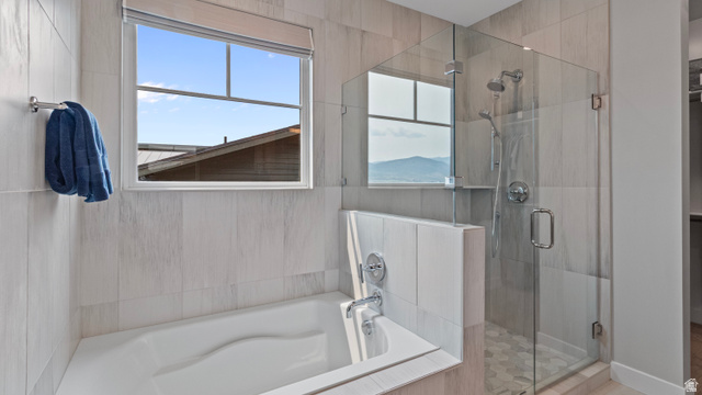 355 East Overlook Loop Hideout, UT 84036 - Photo 19 of 40 Primary suite's modern bathroom featuring a built-in tub, a glass-enclosed shower with a rainfall showerhead, and light-toned tile finishes