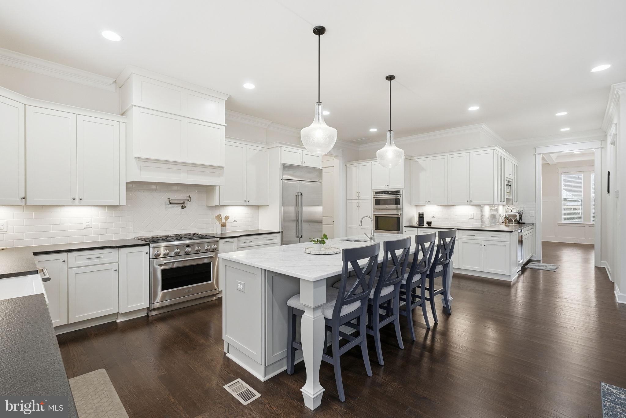 2867 Hill Road Vienna, VA 22181 - Photo 9 of 70 a kitchen with stainless steel appliances kitchen island granite countertop a stove a sink a dining table and chairs with wooden floor