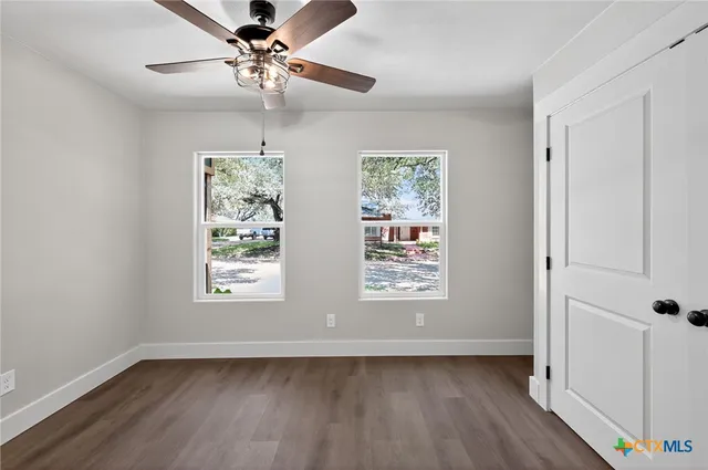 a view of an empty room with wooden floor and a window