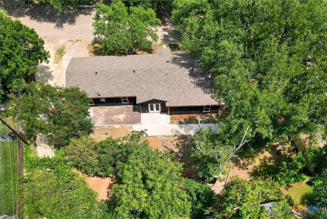 an aerial view of a house with yard and trees all around