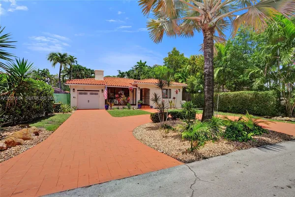 a front view of a house with a yard and potted plants