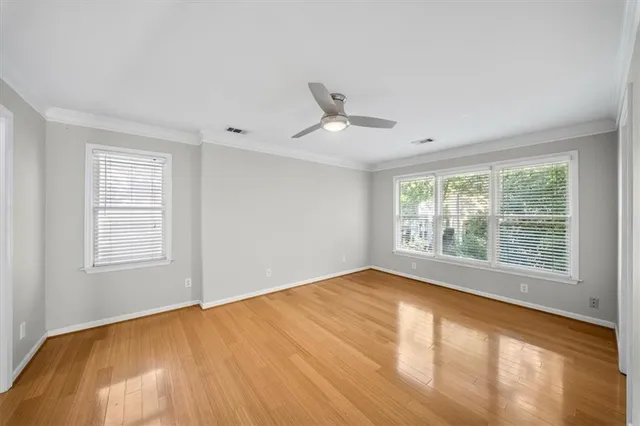an empty room with a chandelier fan and wooden floor