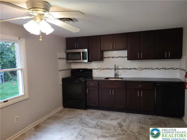 a kitchen with granite countertop a refrigerator a stove a sink and dishwasher with wooden floor