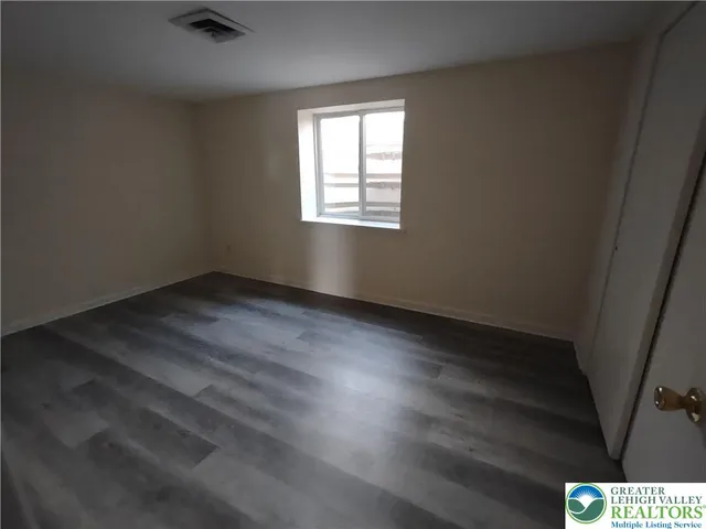 an empty room with wooden floor windows and closet