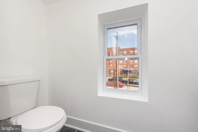 a white toilet sitting next to a small window