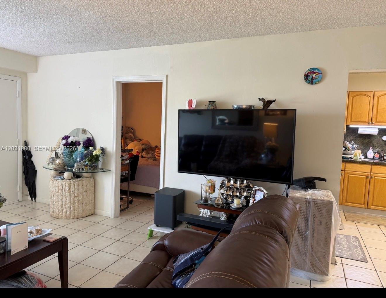 12860 Southwest 43rd Drive, Unit 146B Miami, FL 33175 - Photo 11 of 12 a living room with furniture and a flat screen tv
