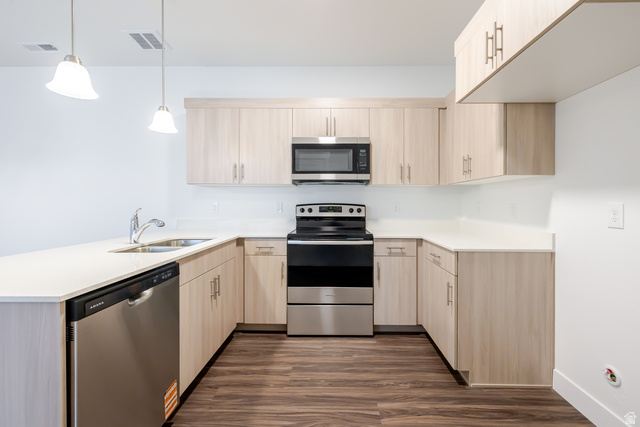 709 West 4500th South, Unit N302 Mapleton, UT 84664 - Photo 9 of 15 Kitchen featuring stainless steel appliances, a peninsula, dark wood finished floors, light wood finish cabinetry, and decorative light fixtures