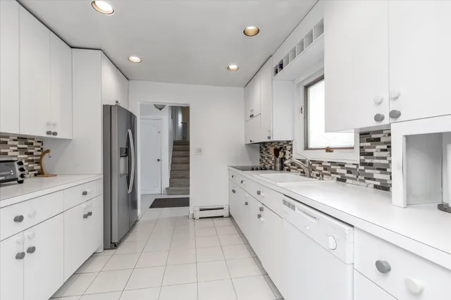 a kitchen with granite countertop white cabinets and stainless steel appliances