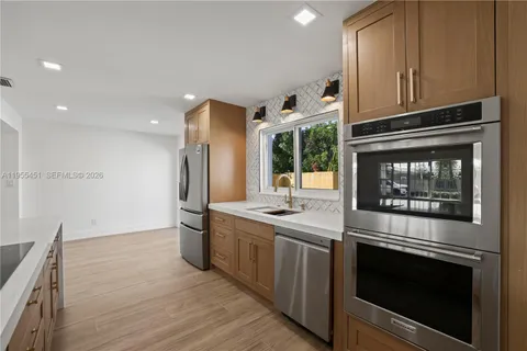 a view of a hallway with wooden floor and a bathroom