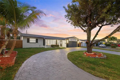 a large kitchen with a large counter top kitchen island a sink a refrigerator and a counter top space