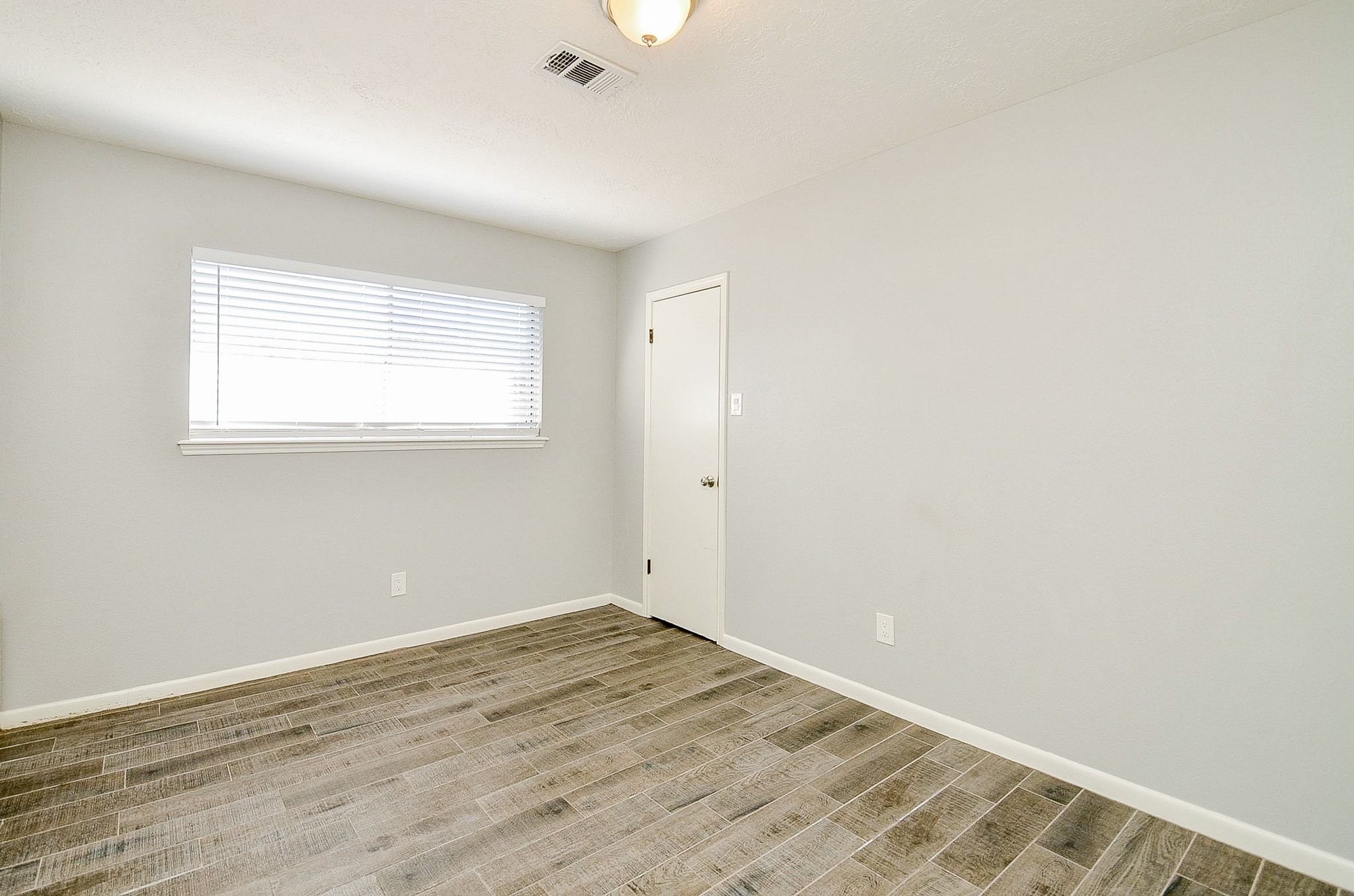 9215 Sharpcrest Street Houston, TX 77036 - Photo 17 of 31 an empty room with wooden floor and windows