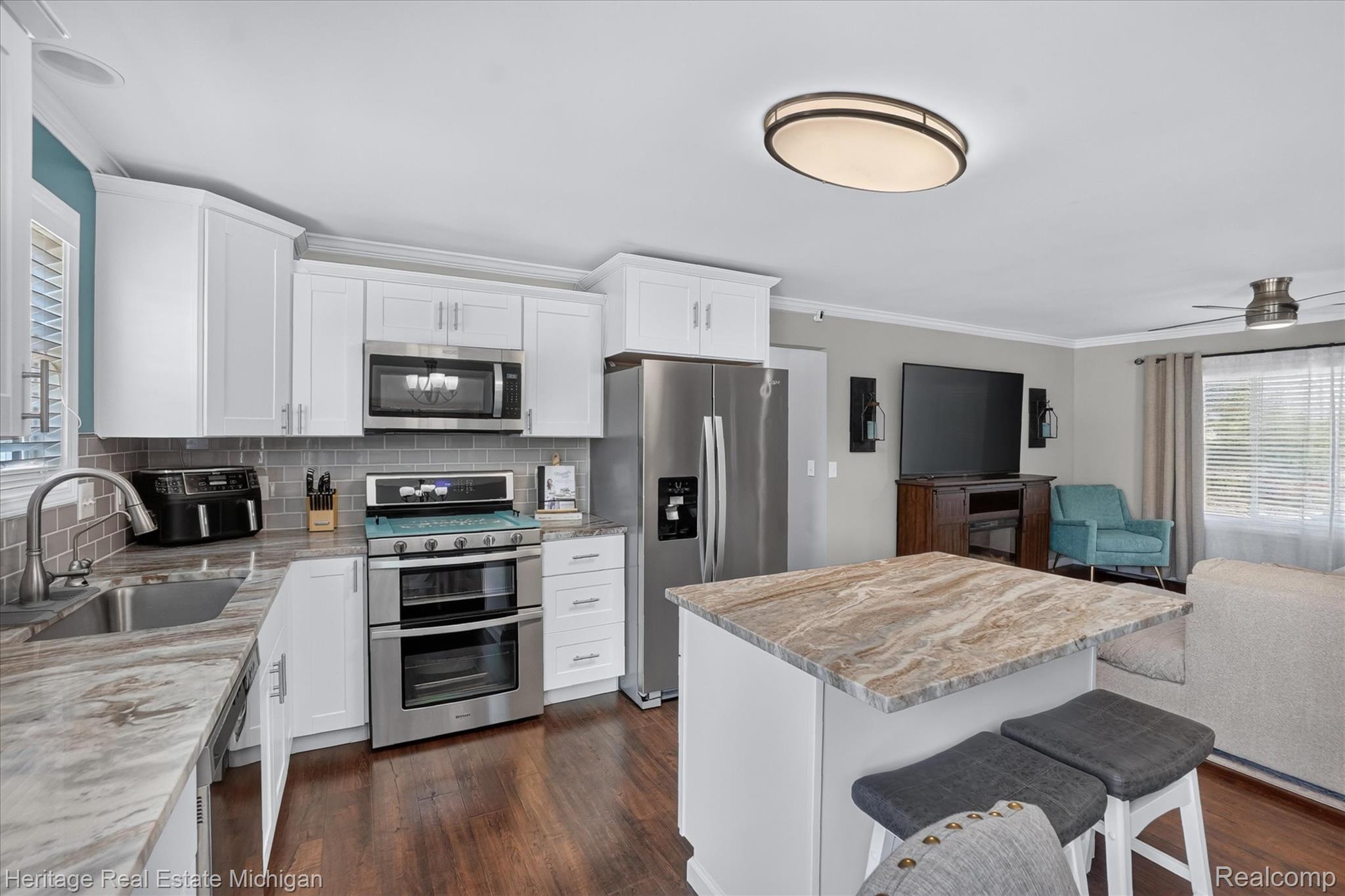 7225 Baldwin Road Swartz Creek, MI 48473 - Photo 8 of 44 Modern kitchen featuring white shaker cabinetry, stainless steel appliances, a subway tile backsplash, and wood-finish flooring
