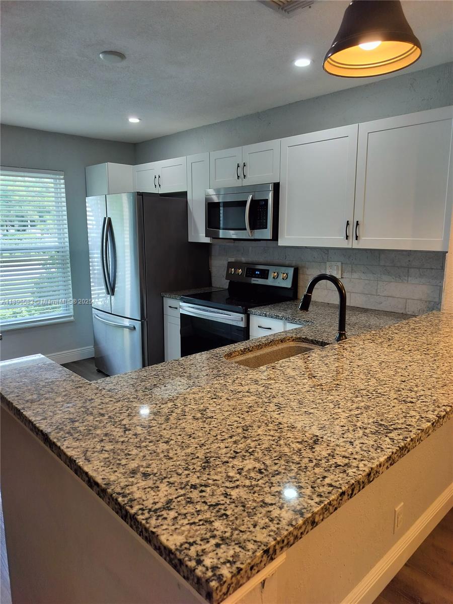 Jupiter Village II Jupiter, FL 33458 - Photo 2 of 9 a kitchen with stainless steel appliances granite countertop a sink stove and refrigerator
