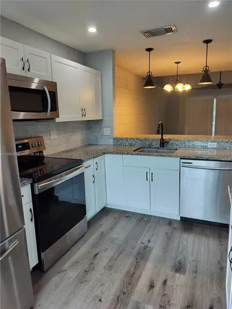 a kitchen with granite countertop a sink stainless steel appliances and cabinets