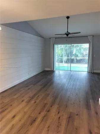 a view of empty room with wooden floor ceiling fan and window