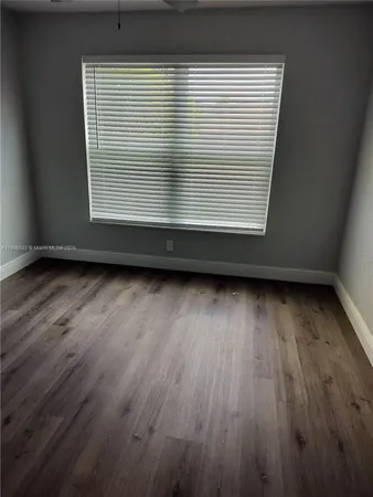an empty room with wooden floor and a window