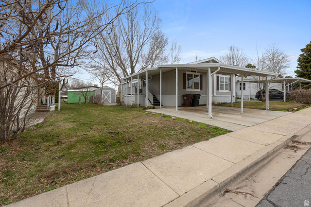 2600 North Hill Field Road, Unit 134 Layton, UT 84041 - Photo 4 of 41 View of front of home with a front yard, a carport, a storage unit, and covered porch