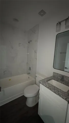 a bathroom with a granite countertop sink a toilet and bathtub