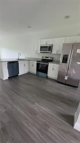 a large white kitchen with wooden floors and stainless steel appliances