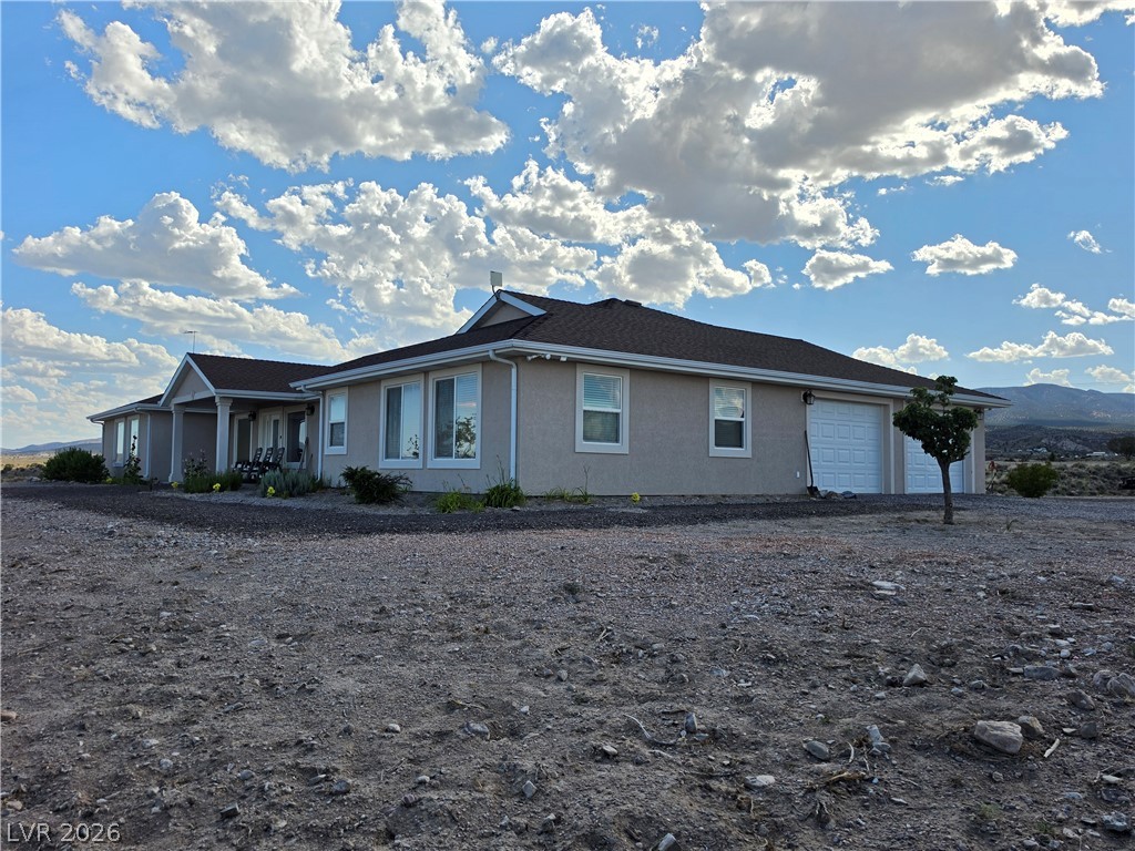 5272 Truman Lane Caliente, NV 89008 - Photo 40 of 43 A well-maintained stucco residence nestled amidst natural desert landscape, complete with an attached two-car garage.