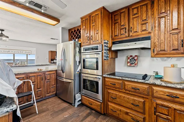 a kitchen with stainless steel appliances granite countertop a refrigerator and wooden cabinets