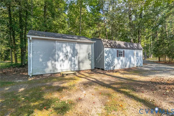 a backyard of a house with large trees and wooden fence