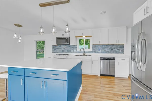 a kitchen with kitchen island granite countertop a sink cabinets stainless steel appliances and a counter top space