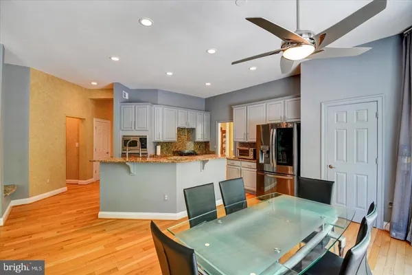 a kitchen with stainless steel appliances granite countertop a refrigerator a stove top oven a sink dishwasher and white cabinets with wooden floor