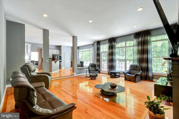a living room with stainless steel appliances furniture a flat screen tv and kitchen view
