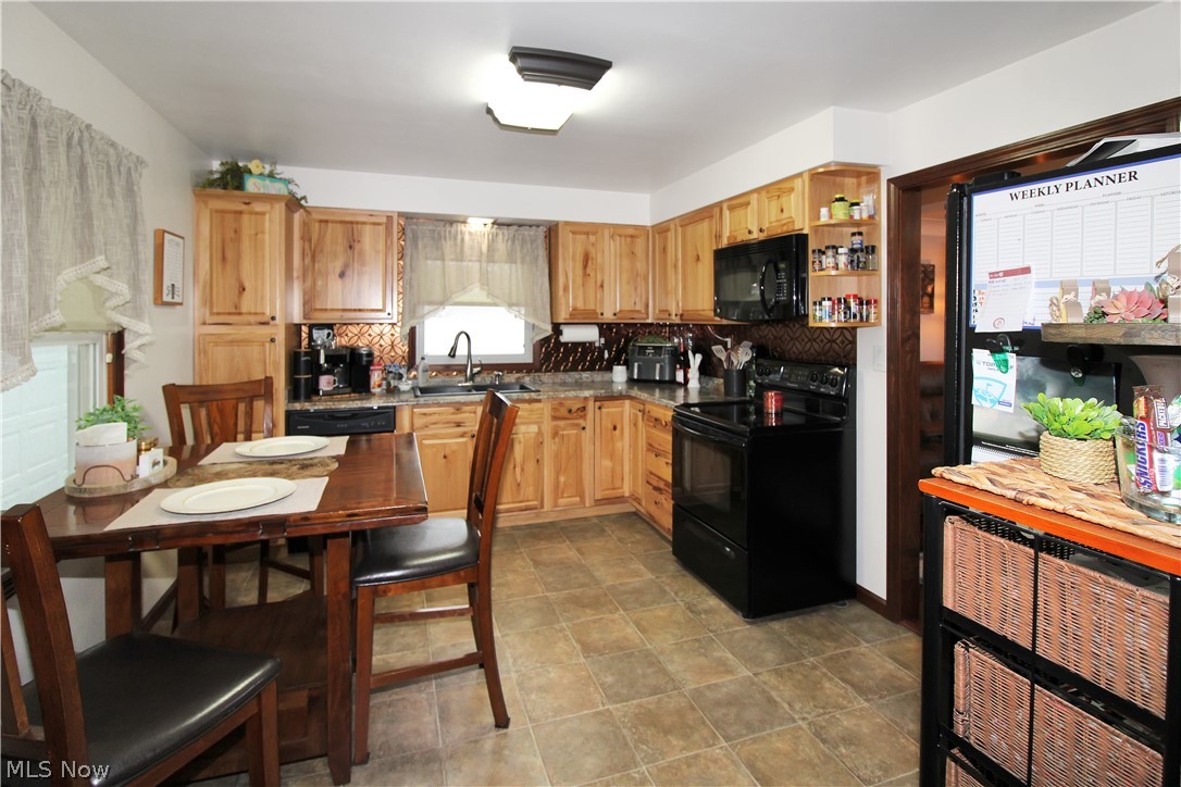 38 Meachem Road Port Clinton, OH 43452 - Photo 22 of 35 Kitchen featuring black appliances, backsplash, sink, and light tile flooring