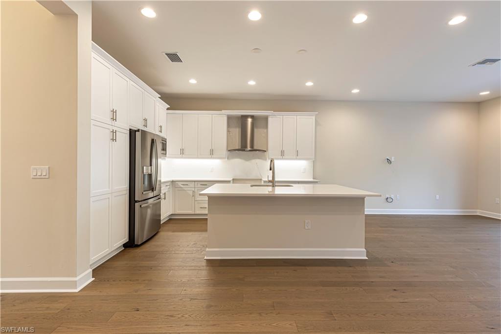 2691 Ridgecrest Place Naples, FL 34112 - Photo 11 of 27 a large kitchen with stainless steel appliances a large counter top a refrigerator and a sink