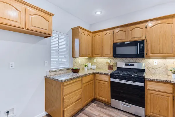 a kitchen with stainless steel appliances granite countertop a stove a sink and a microwave