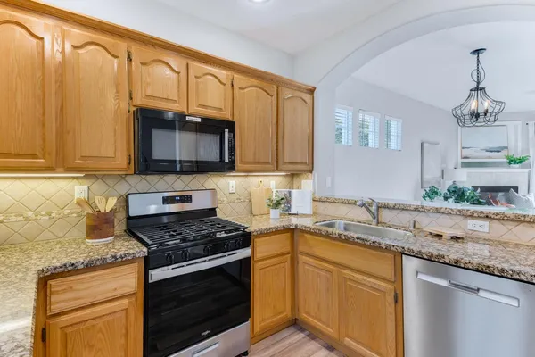 a kitchen with granite countertop a stove sink and microwave