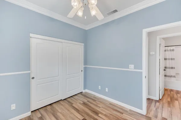 an empty room with wooden floor cabinet and windows