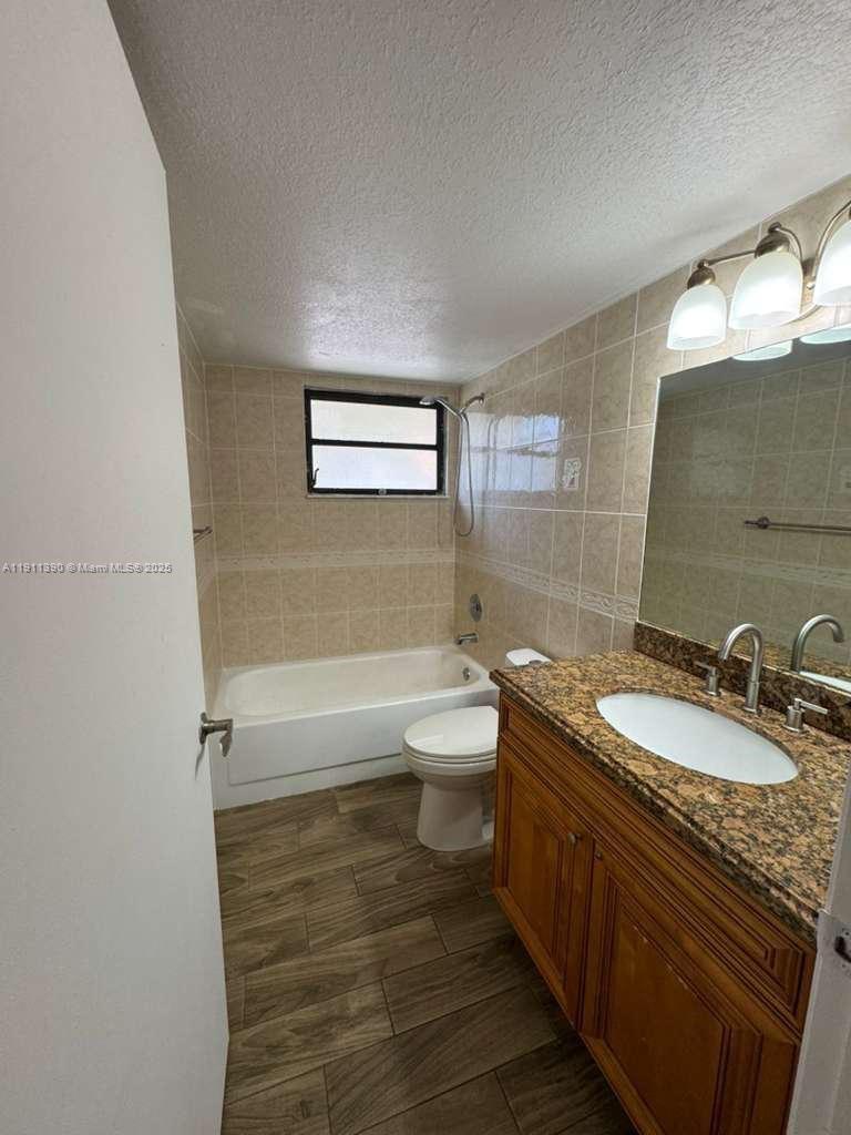 1580 Windorah Way, Unit E West Palm Beach, FL 33411 - Photo 16 of 20 a bathroom with a granite countertop toilet a sink and a bathtub
