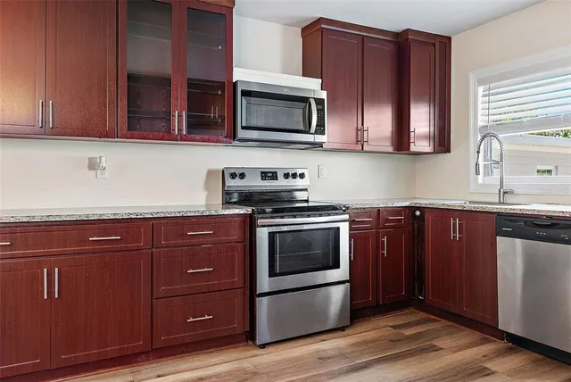 a kitchen with stainless steel appliances granite countertop wooden cabinets and a stove top oven